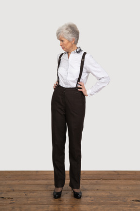 Front view of a pouting old lady in office clothing putting hands on hips