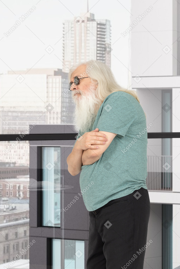 A man with a long white beard standing in front of a window