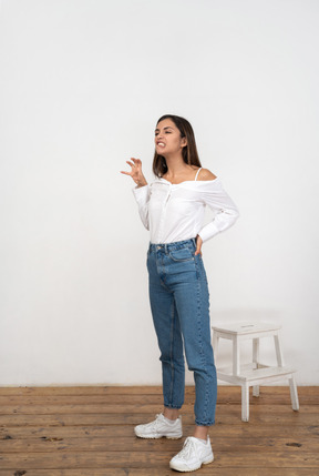 Woman in white shirt and jeans standing and making faces