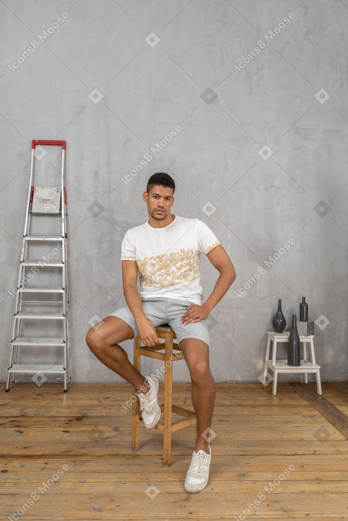 Front view of young man sitting on chair and looking at camera