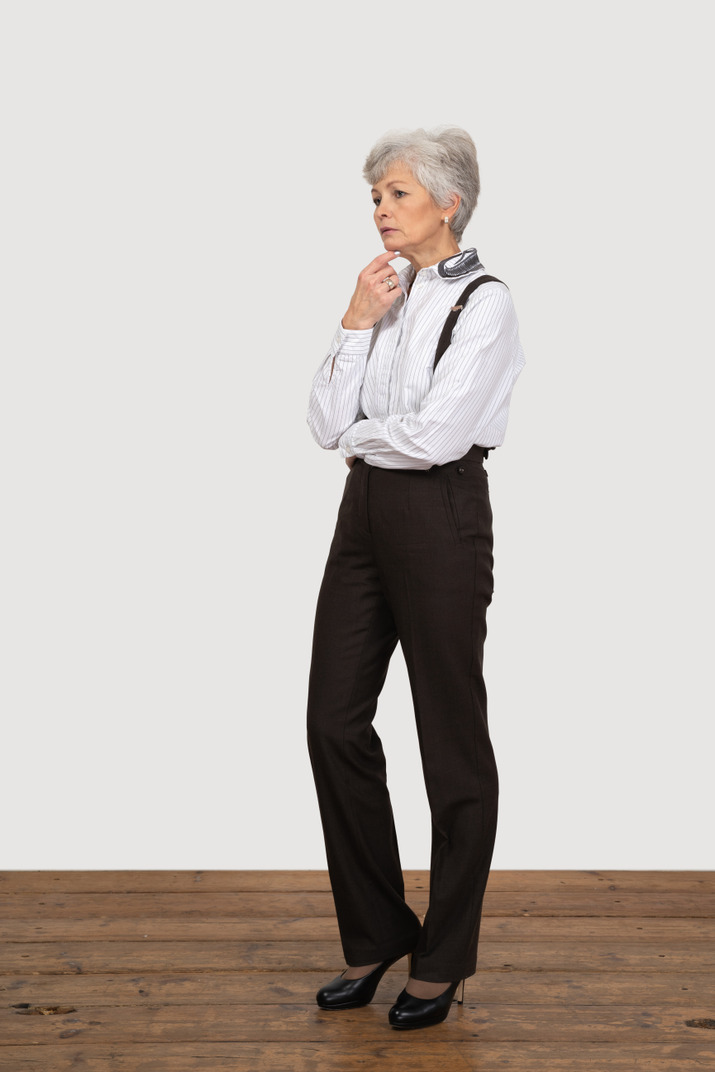 Three-quarter view of a thoughtful old lady in office clothing touching her chin