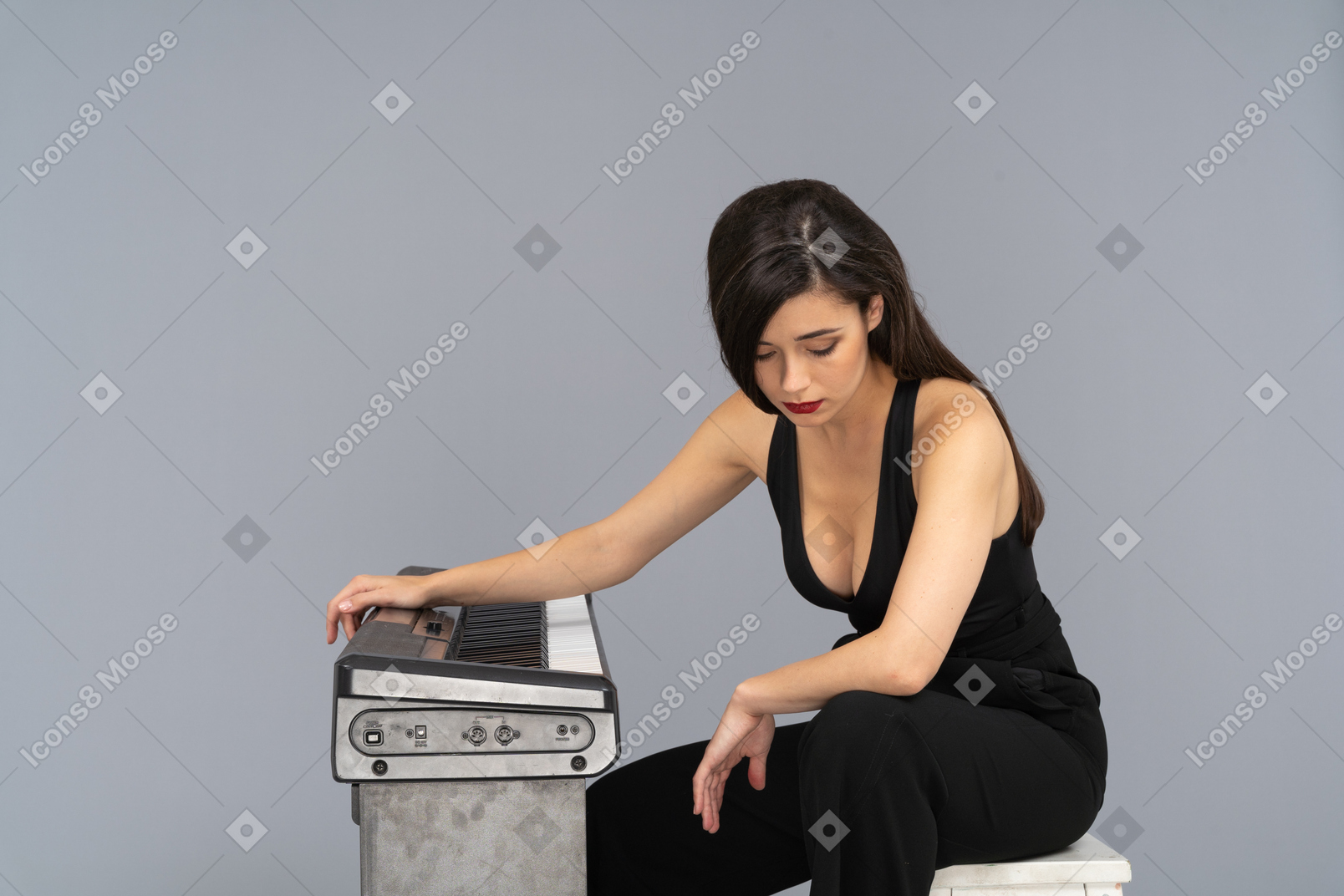 A figura intera di una giovane donna triste seduta al pianoforte mentre guarda verso il basso