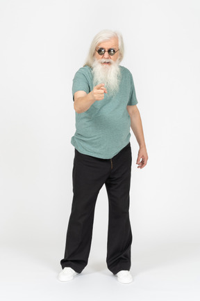 Vue de face du vieil homme à lunettes de soleil pointant vers la caméra