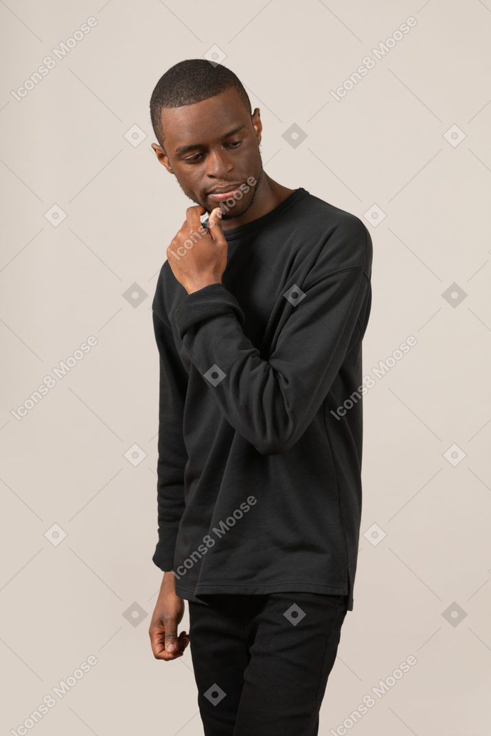 Young guy touching his chin and looking down