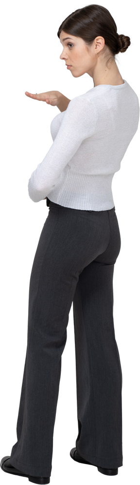Three-quarter back view of a young woman in office clothing showing size of something