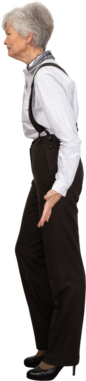 Вид сбоку гримасничающей старушки в офисной одежде, раскинувшей руки