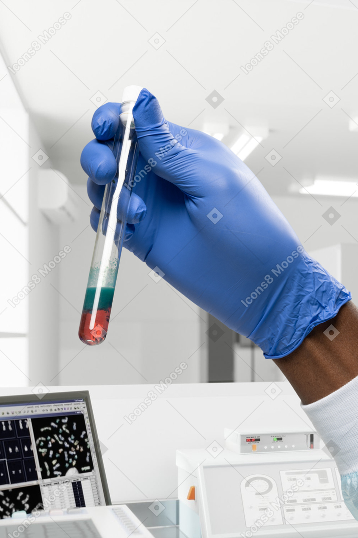 Hand in latex glove holding a test tube with liquid