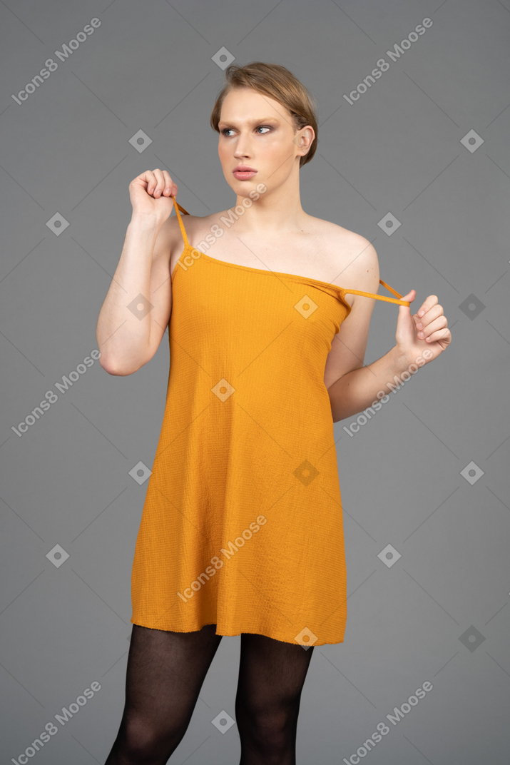 Young transgender person pulling on dress straps