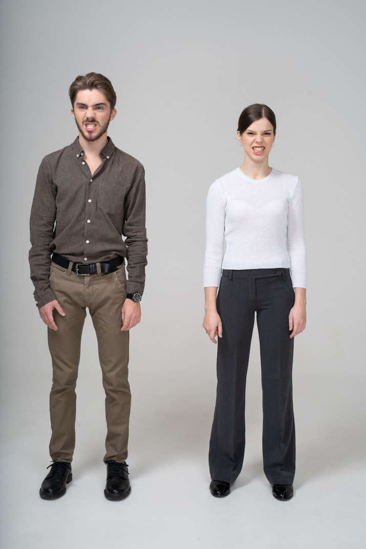 Front view of an angry young couple in office clothing clenching teeth