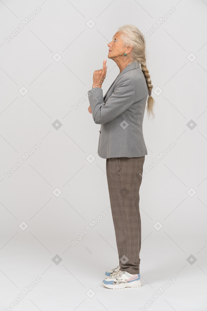 Vista laterale di una vecchia signora in abito che mostra gesto di avvertimento
