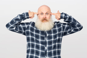 Bearded man holding pointing fingers at his temples