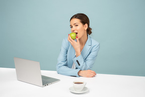 Impiegato attraente seduto al tavolo e mangiare una mela