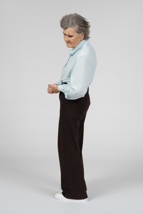 Vista laterale di una donna anziana che guarda tristemente in basso