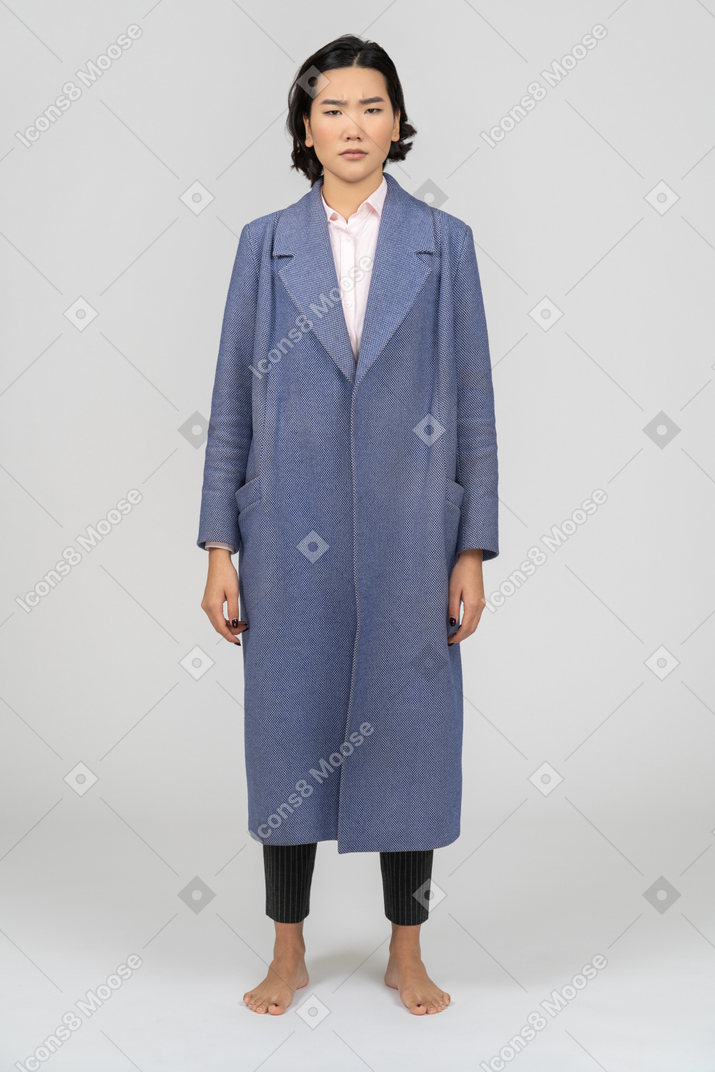 青いコートを着て眉間に皺を寄せた女性の正面図