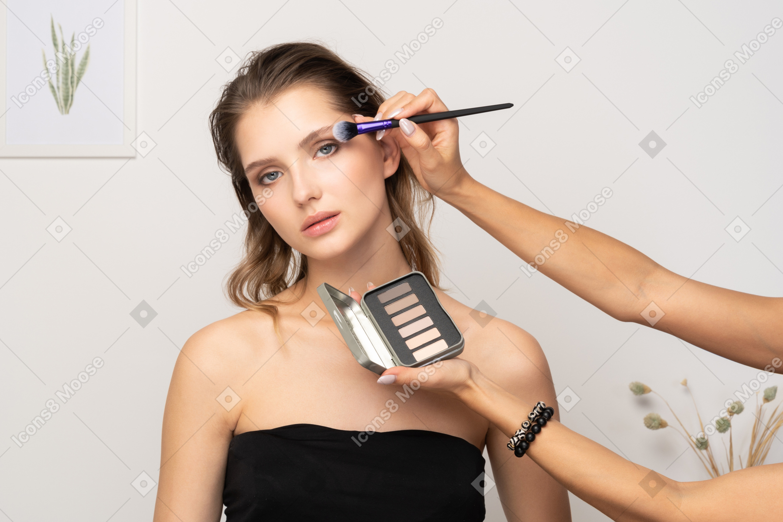 Front view of a make-up artist doing eye make-up for a female model