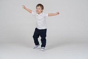 Маленький мальчик прыгает с вытянутыми руками