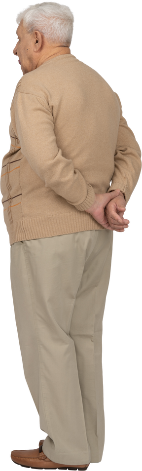 後ろ手で立っているカジュアルな服装の老人の背面図