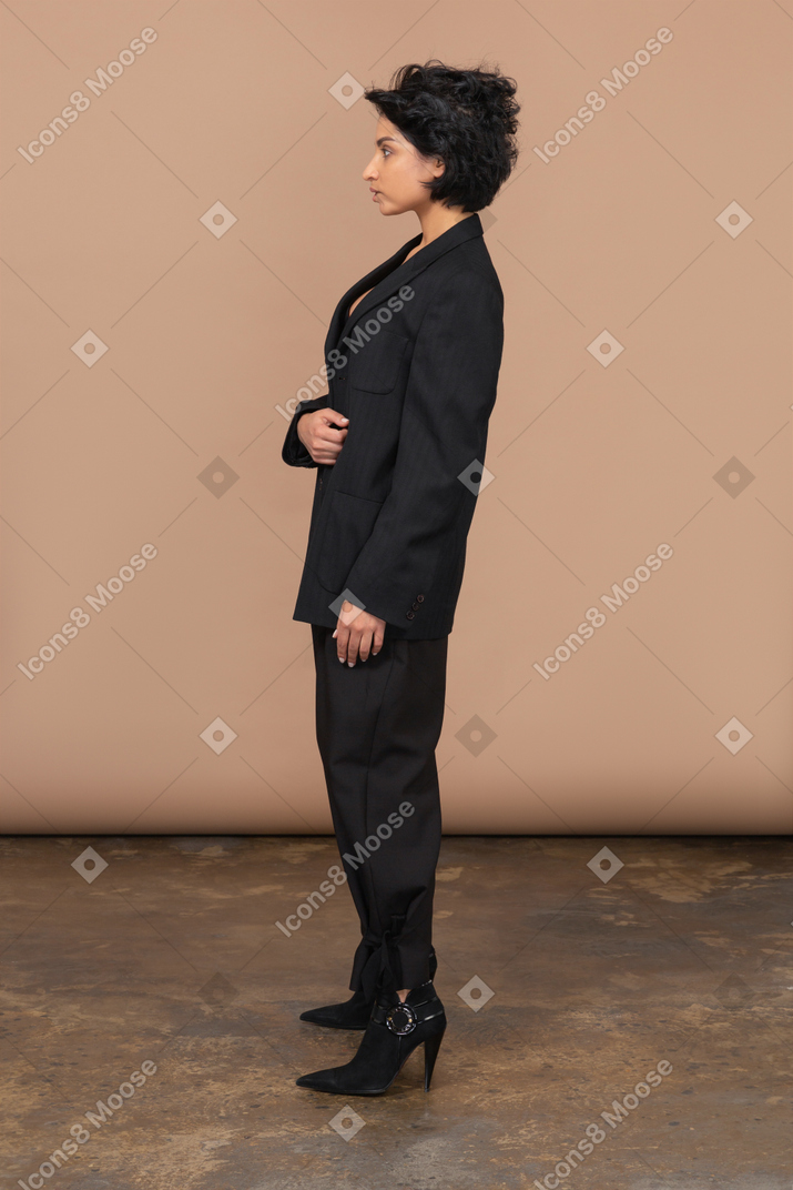 Seitenansicht einer geschäftsfrau, die ihre schwarze jacke hält und zur seite schaut
