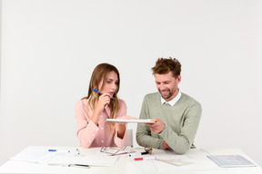Female and male architects sitting at the table and holding tablet