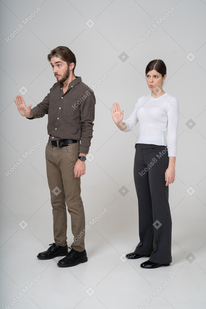 Vista di tre quarti di una giovane coppia in abiti da ufficio mano tesa