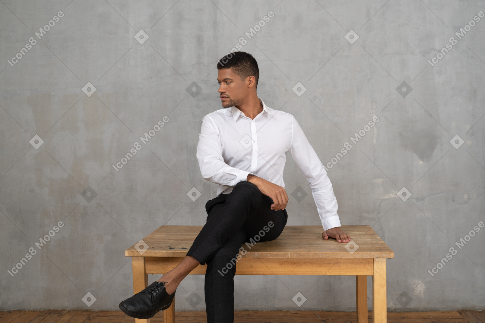 Uomo ben vestito seduto su un tavolo con la testa girata