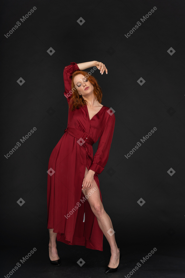 A frontal view of the young woman dressed in red and posing on the black background