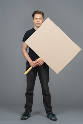 Joven serio de pie con un cartel en blanco