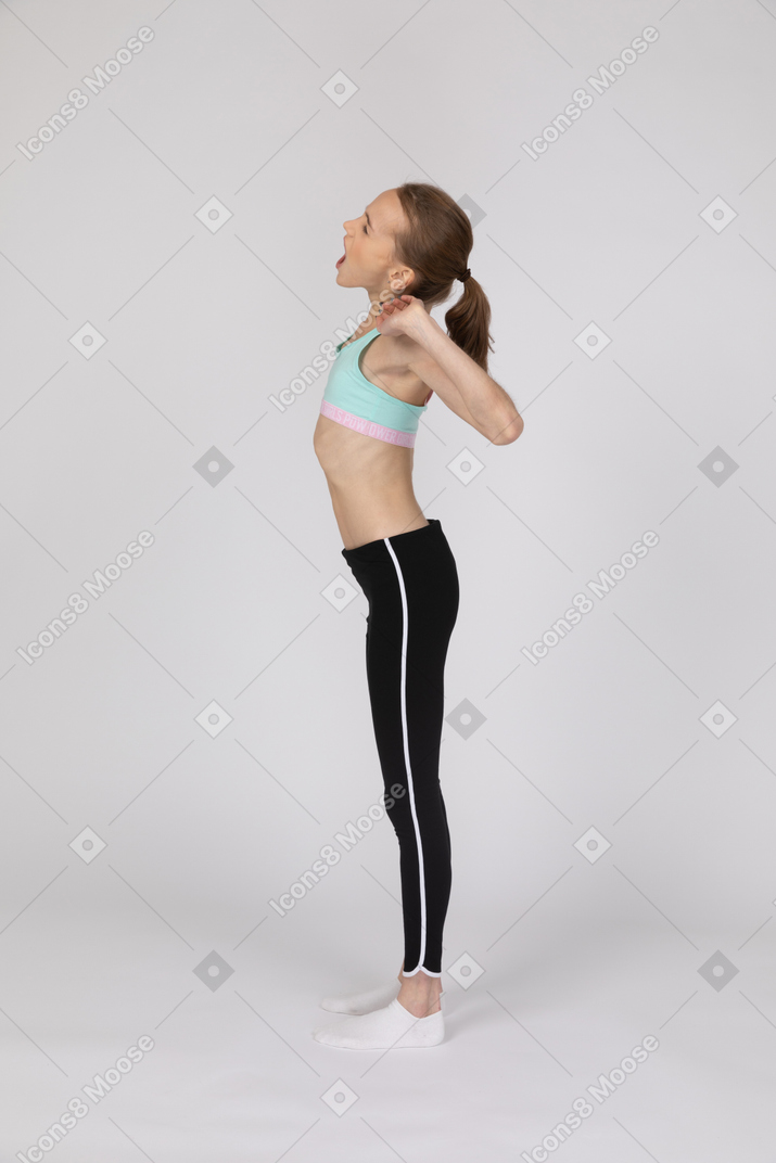 Vista lateral de una adolescente en ropa deportiva bostezando