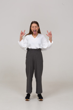 Vue de face d'un jeune rocker crier dans des vêtements de bureau montrant la langue