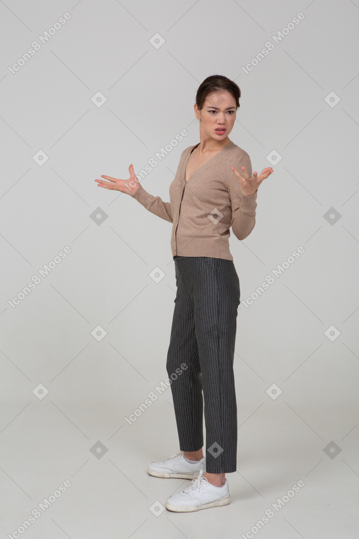 Вид в три четверти вопрошающей жестикулирующей молодой леди в бежевом пуловере
