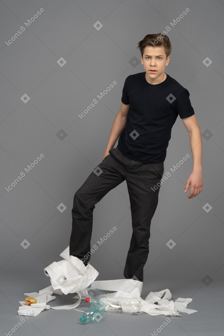 Puzzled man among garbage on gray background