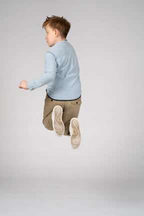 Back view of a boy jumping high in the air