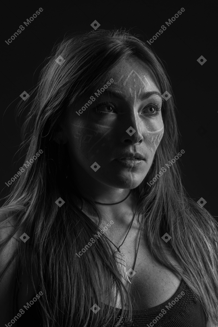 Three-quarter dark portrait of a young  hopeful woman with face art