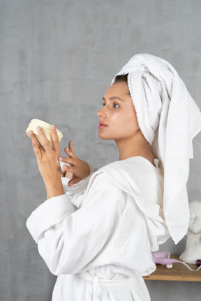 ハンドクリームを塗るバスローブ姿の女性の側面図