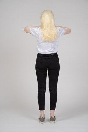 Back view of a long-haired woman pressing hands to head