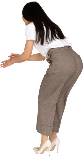 Three-quarter back view of a questioning  young lady in breeches and t-shirt raising hands and bending down
