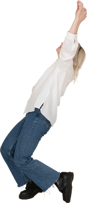 Vista lateral de una mujer rubia en ropa casual de puntillas cayendo y levantando las manos