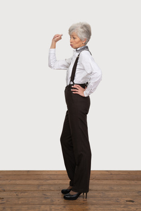 Vista lateral de uma senhora idosa com roupa de escritório levantando a mão