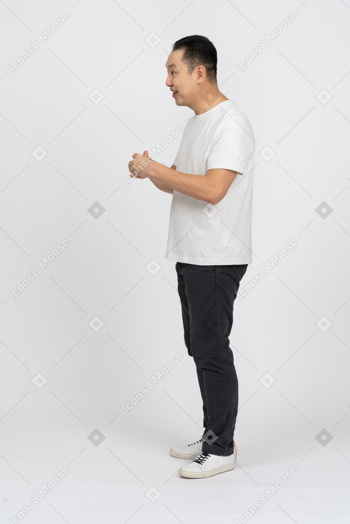 Side view of a happy man in casual clothes rubbing hands