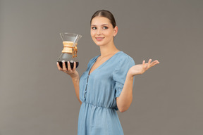 Three-quarter view of a young woman in blue dress holding a pitcher of wine