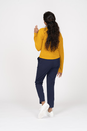 Rear view of a girl in casual clothes showing ok sign