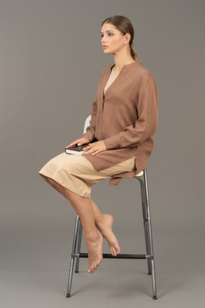 Jeune femme avec un livre assis sur une chaise
