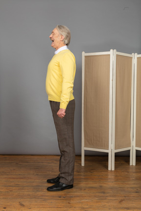 Side view of a screaming old man standing still