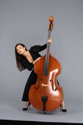 Front view of a young lady squatting behind her double-bass