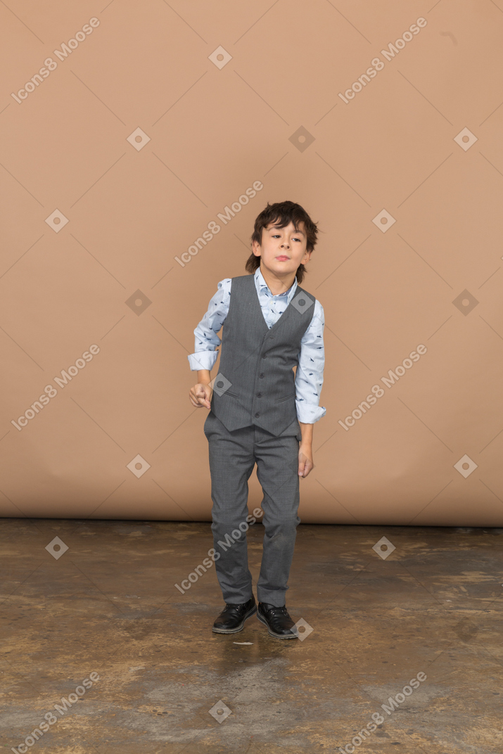 Front view of a cute boy in suit dancing