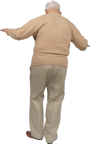 腕を伸ばして歩くカジュアルな服装の老人の背面図