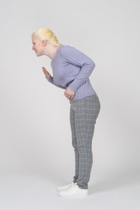 Vista lateral de la mujer joven que gime con dolor de estómago
