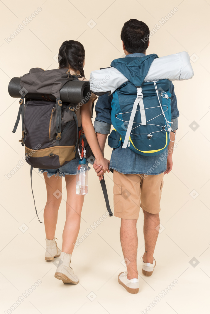 Young woman and man with backpacks holding hands