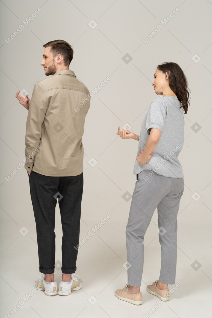 Three-quarter back view of young couple luring with finger