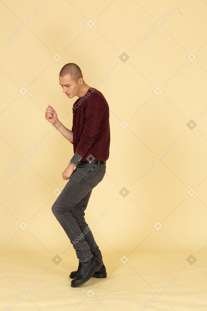 Вид в три четверти усталого танцующего молодого человека в красном пуловере